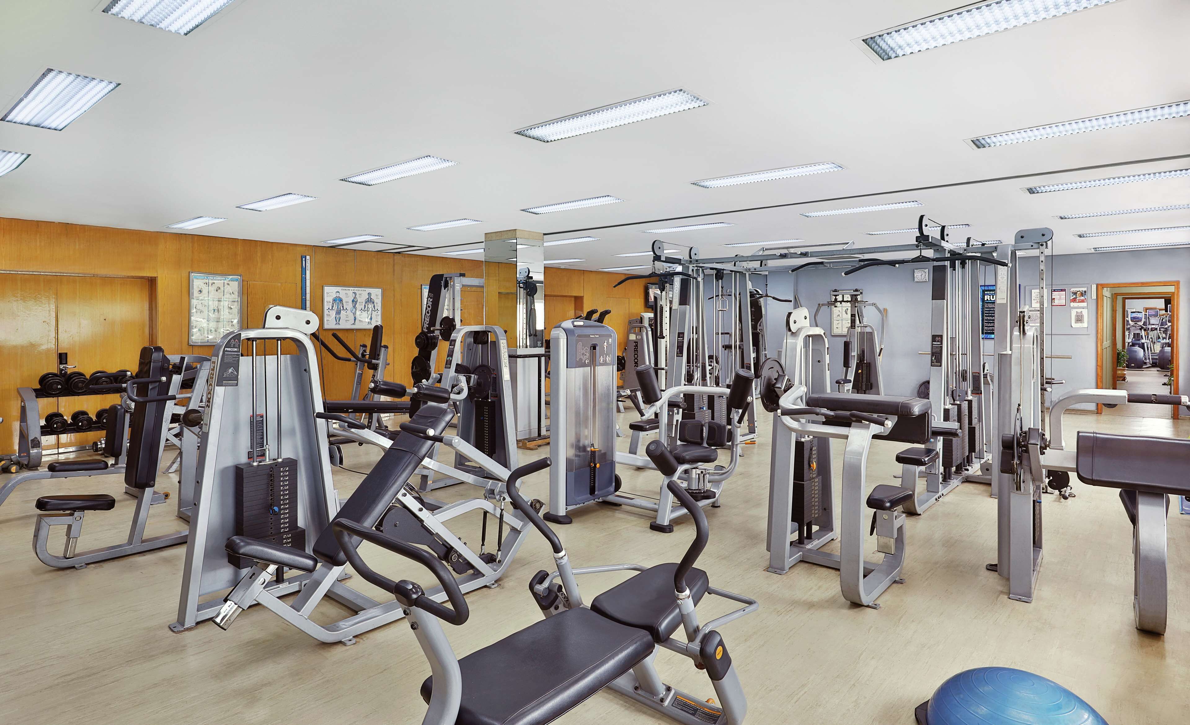 A gym with various exercise machines, weight racks, and a mirror on the wall.