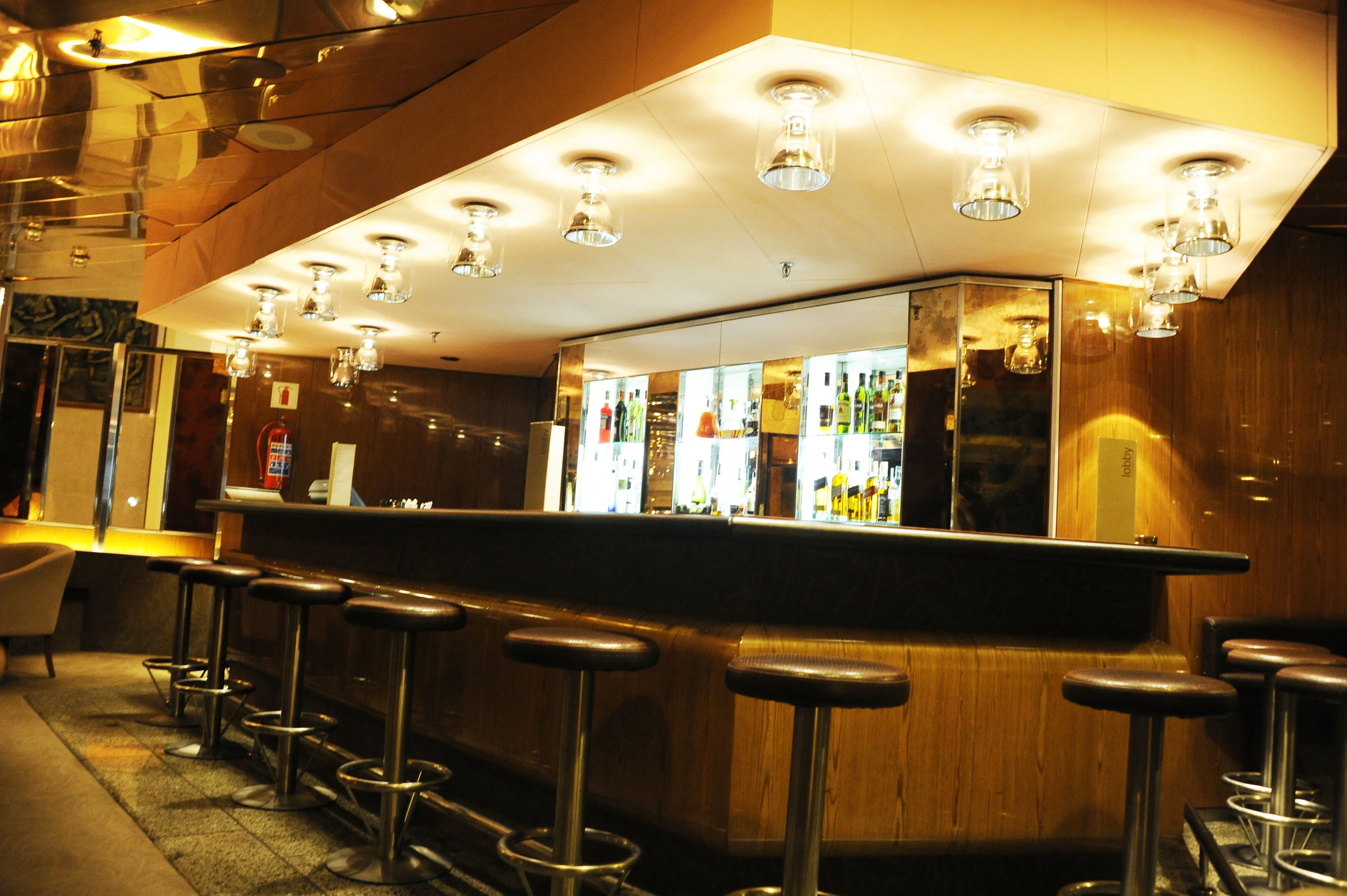 Una zona de bar con barra, taburetes e iluminación colgante.