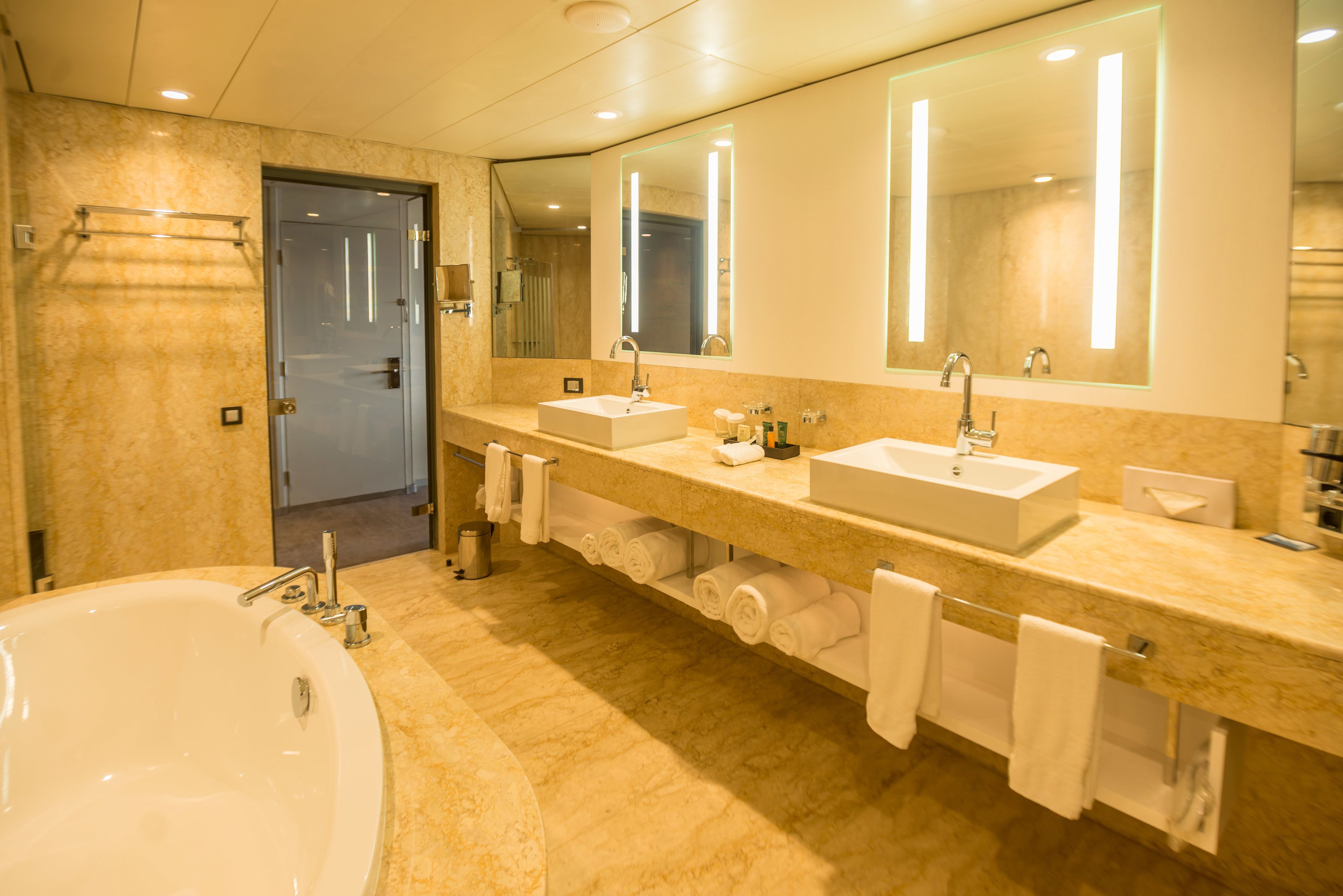 A modern bathroom with a large bathtub, two sinks, and a mirror.