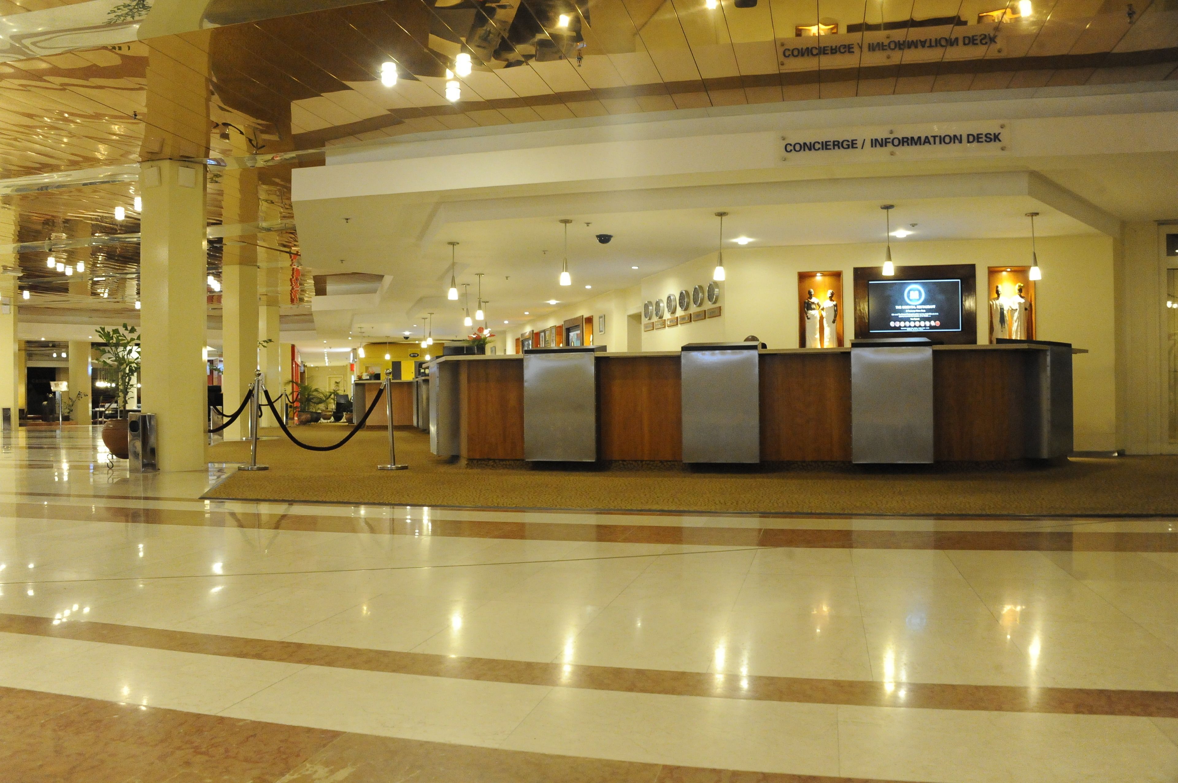 A reception area with a concierge/information desk, a large screen, and a clean, polished floor.