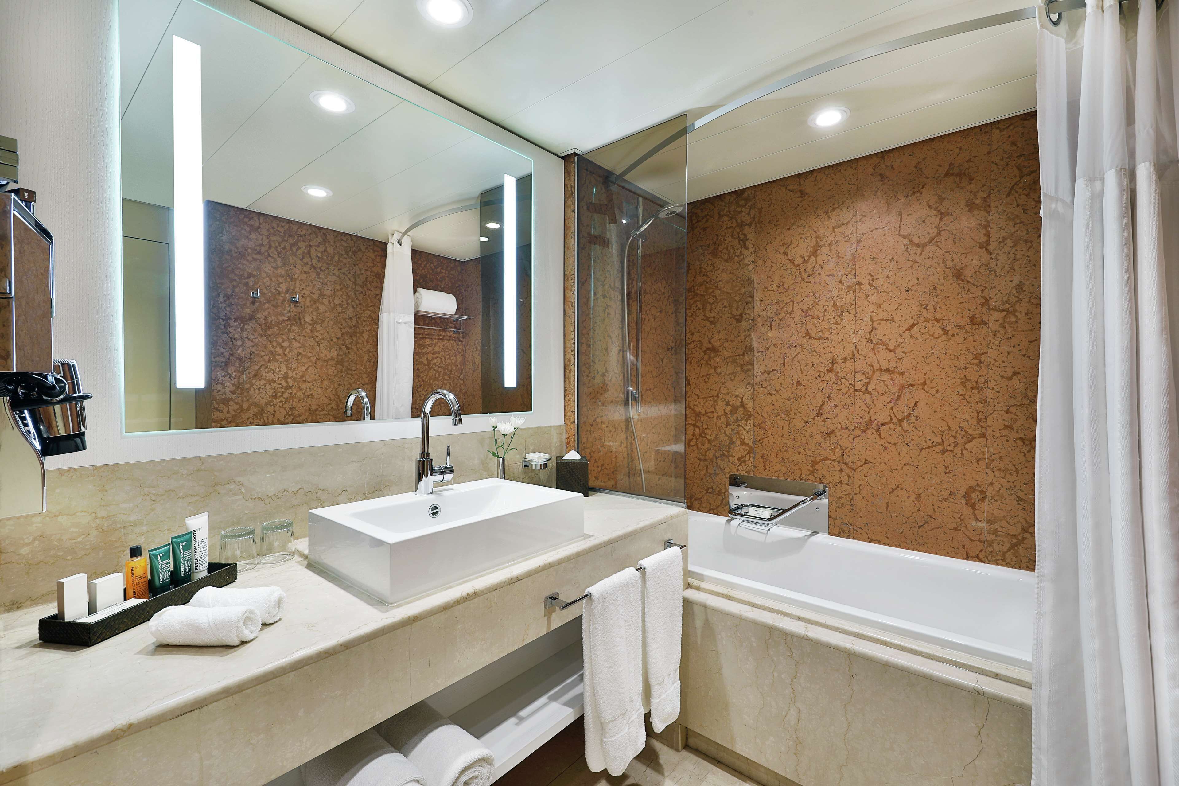 A modern bathroom with a large sink, a bathtub, and a glass shower enclosure.