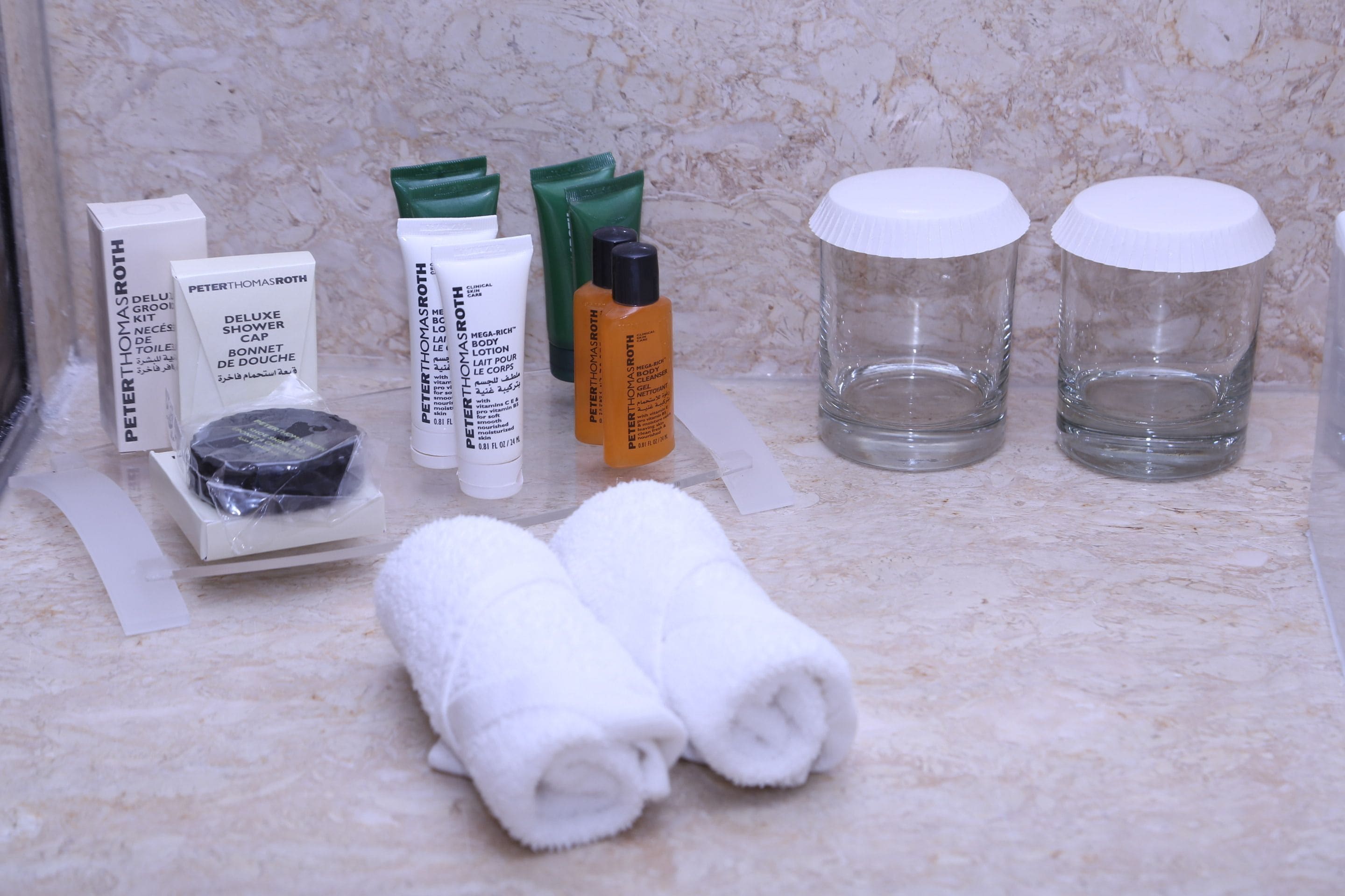Toiletries and towels on a marble countertop.