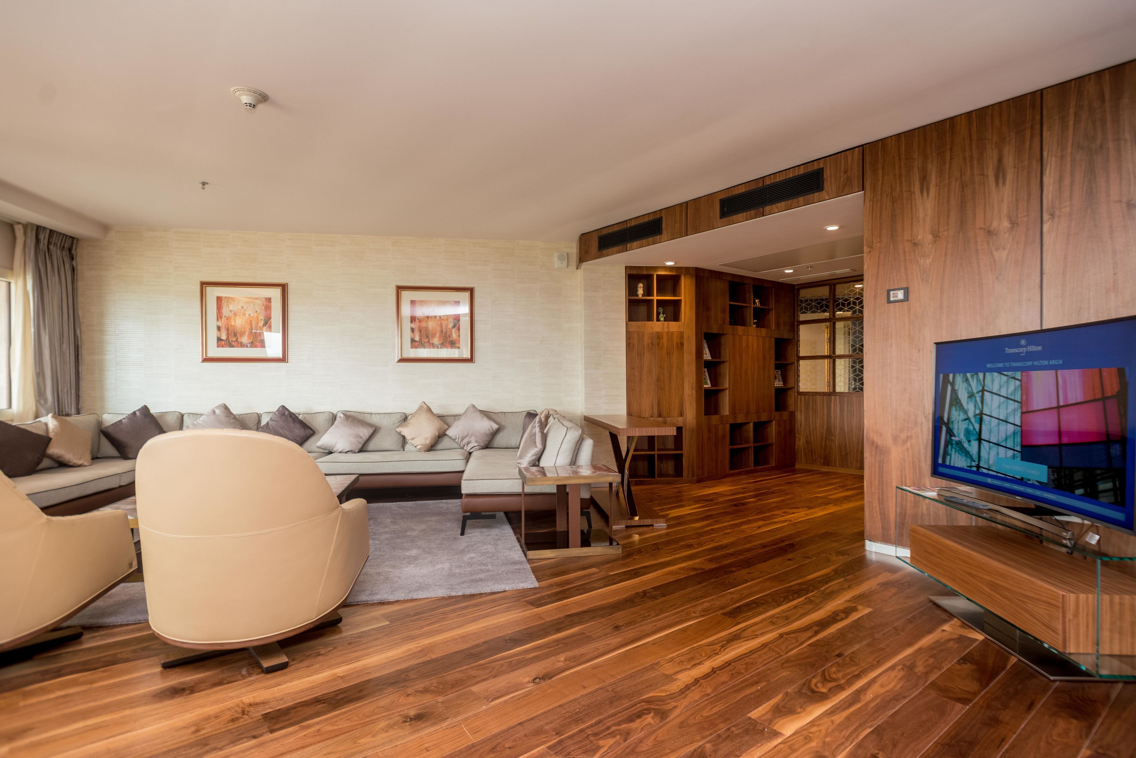 Una sala de estar moderna con un sofá, un sillón y mueble para entretenimiento.
