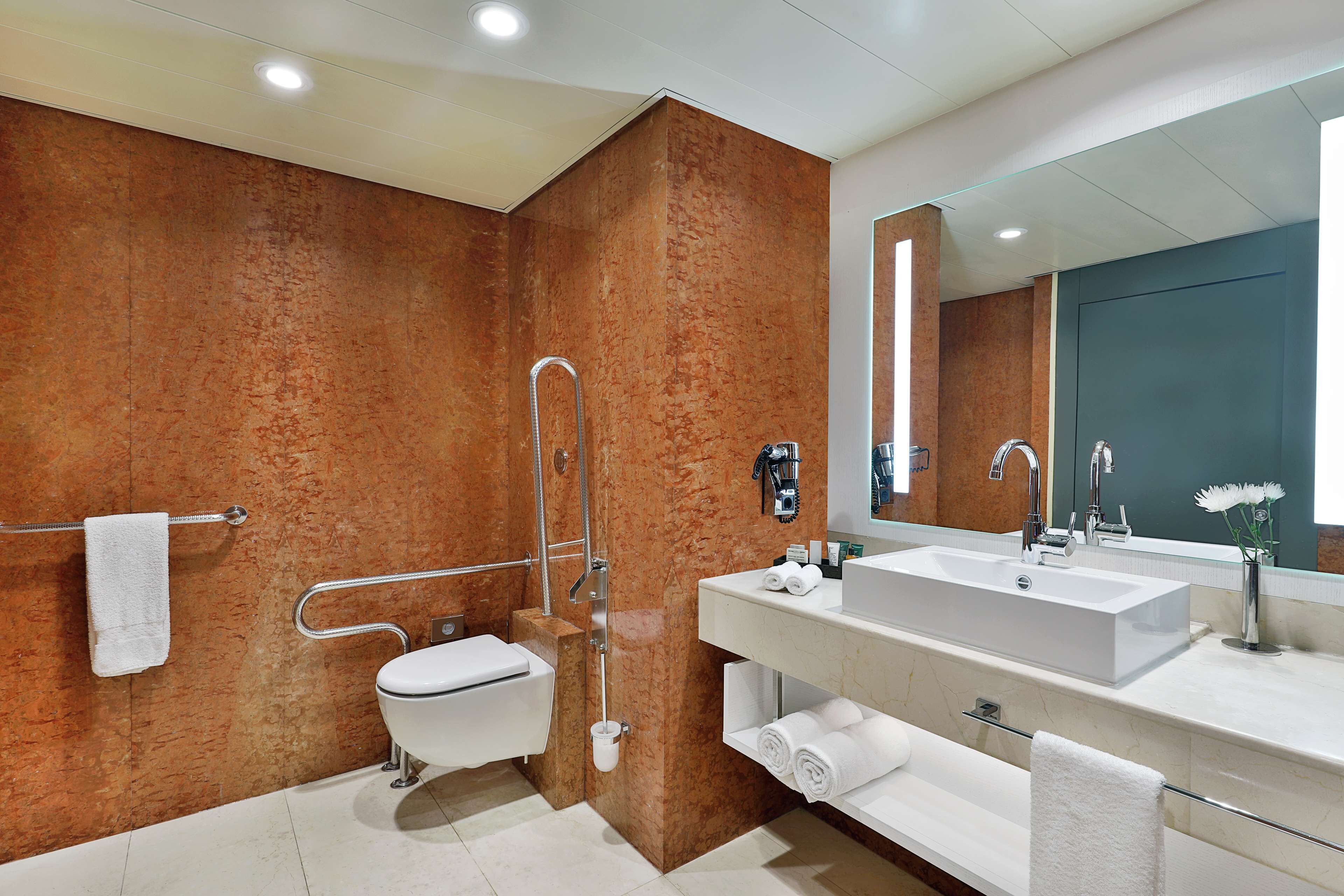 Een moderne badkamer met een witte wastafel, een grote spiegel en een douche met een glazen deur.