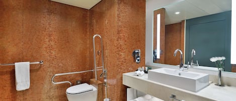 A modern bathroom with a white sink, a large mirror, and a shower with a glass door.