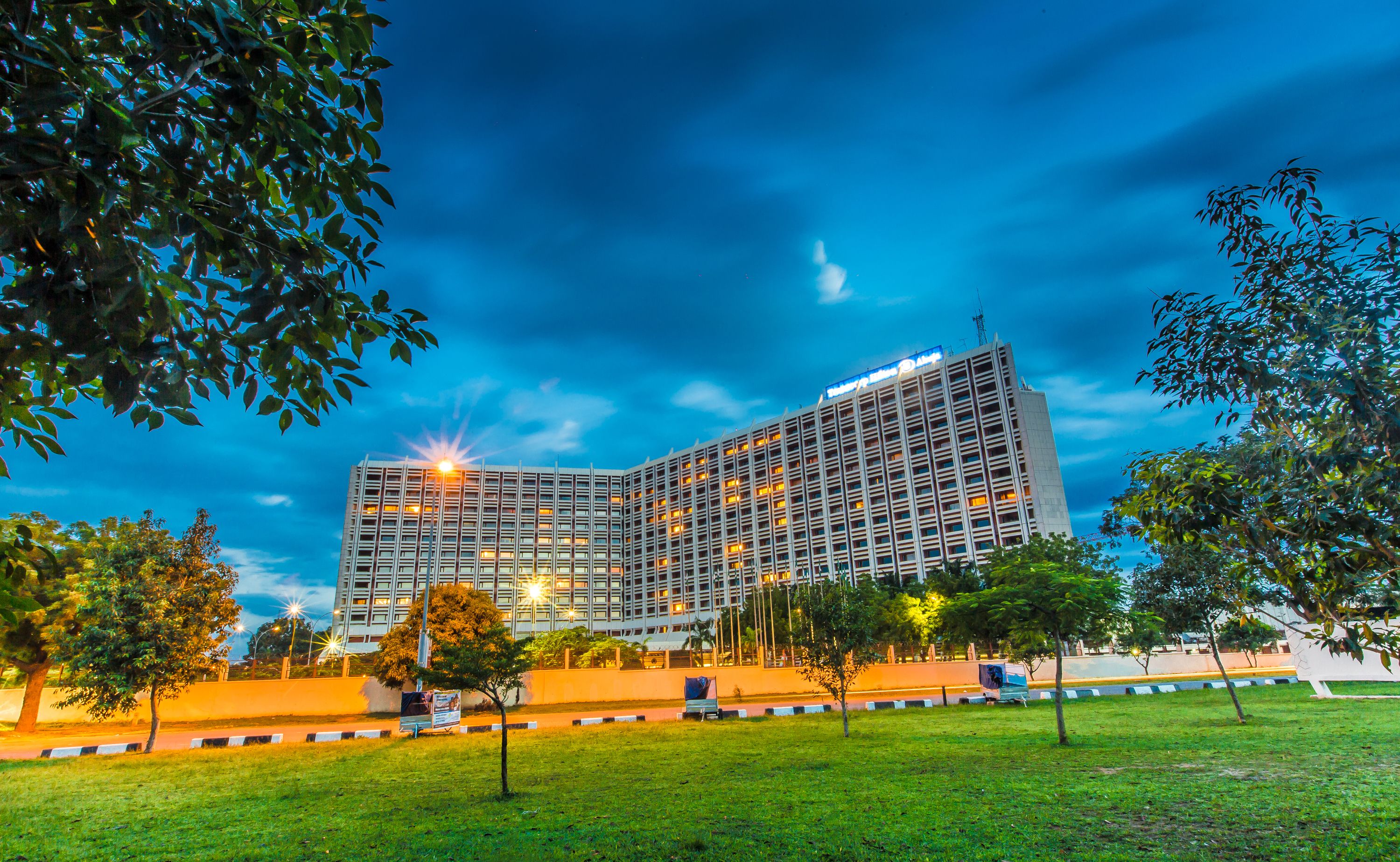 Un hôtel moderne à la façade incurvée, doté de plusieurs étages et d’une entrée bien éclairée.
