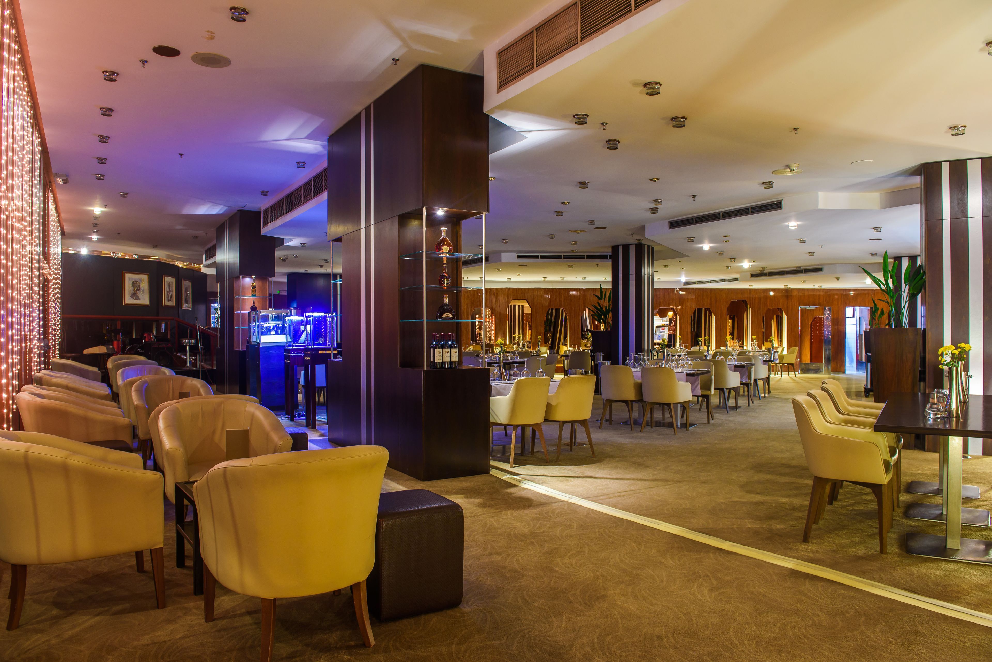 A hotel lobby with a bar area, seating arrangements, and a reception desk.