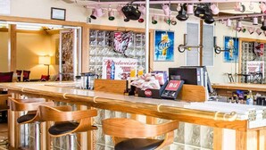 A bar area with wooden stools, a counter, and various beverage advertisements on the wall. - Comfort Inn Bellefontaine (Bellefontaine)