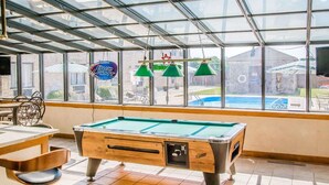 A pool table in a room with large windows, a pool, and outdoor seating. - Comfort Inn Bellefontaine (Bellefontaine)