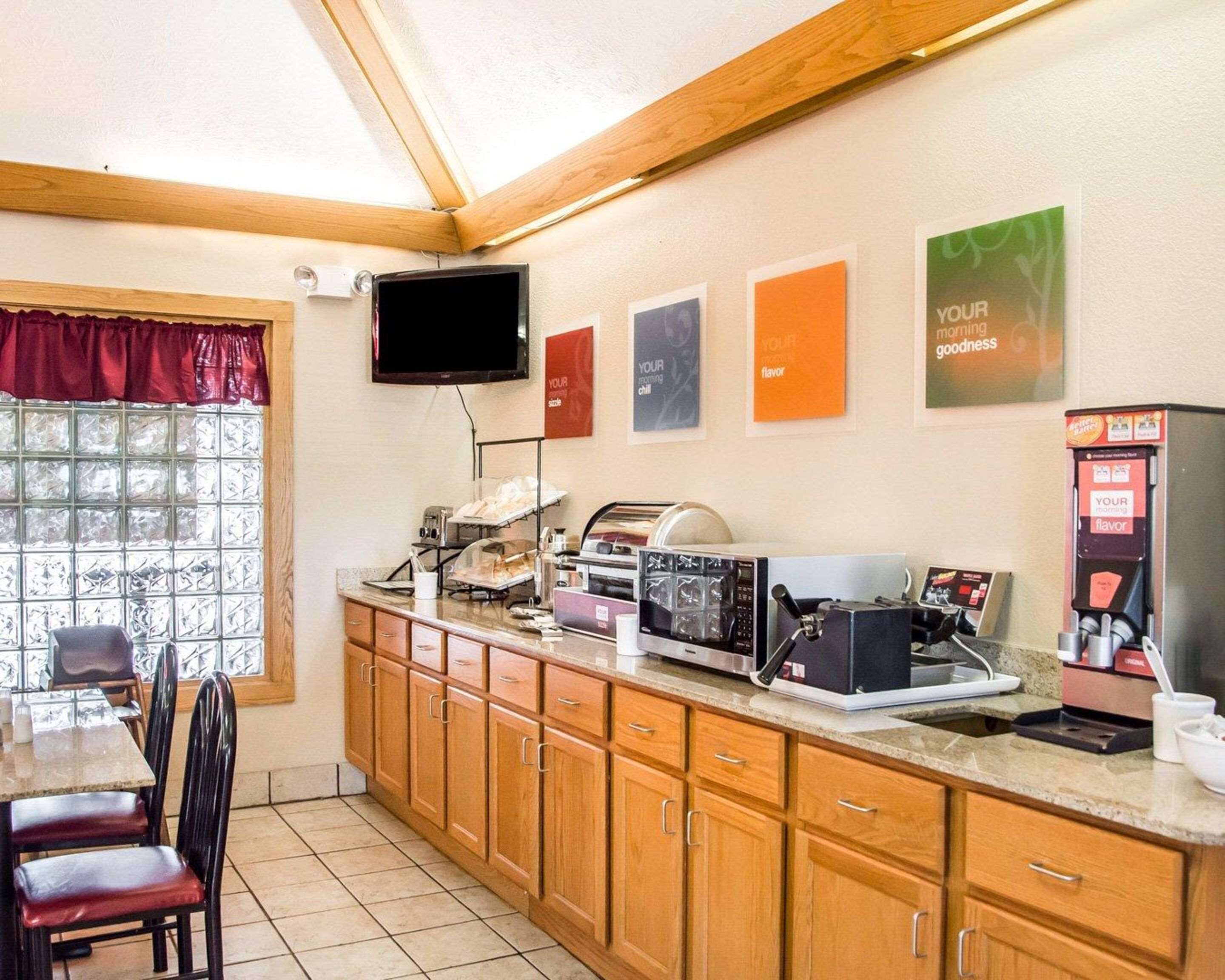 Una zona de desayuno con mostrador, microondas, cafetera y televisor montado en la pared.