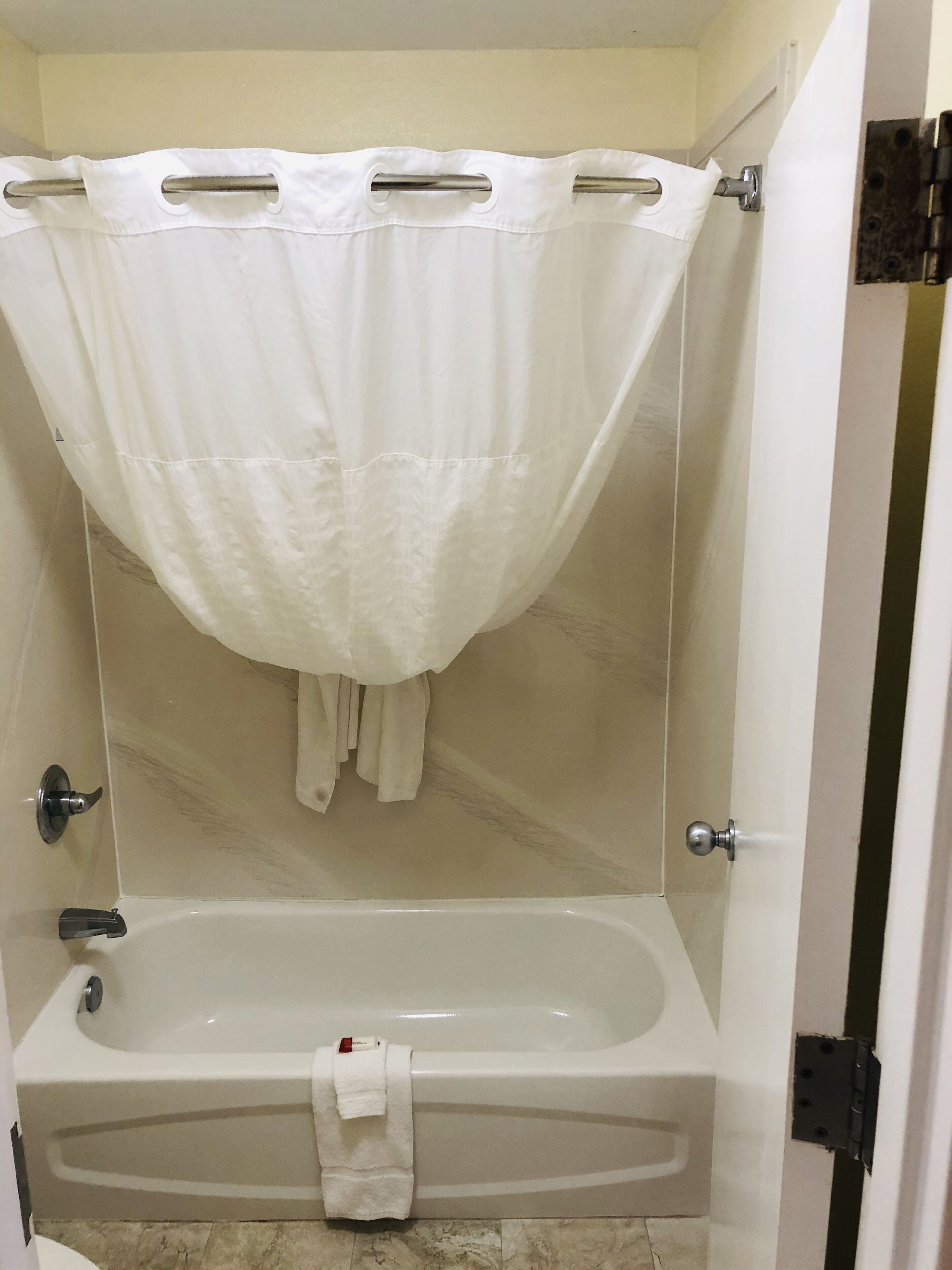 Une salle de bain avec une baignoire, un rideau de douche et une serviette accrochée au mur.