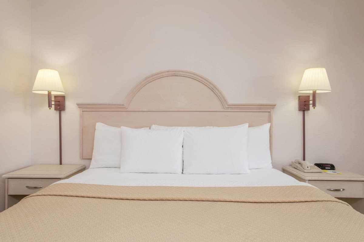 Ein Hotelzimmer mit einem Bett, zwei Nachttischen und einer Lampe auf jeder Seite.