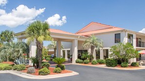 Ein Hotel mit überdachter Einfahrt, Palmen und rotem Dach.