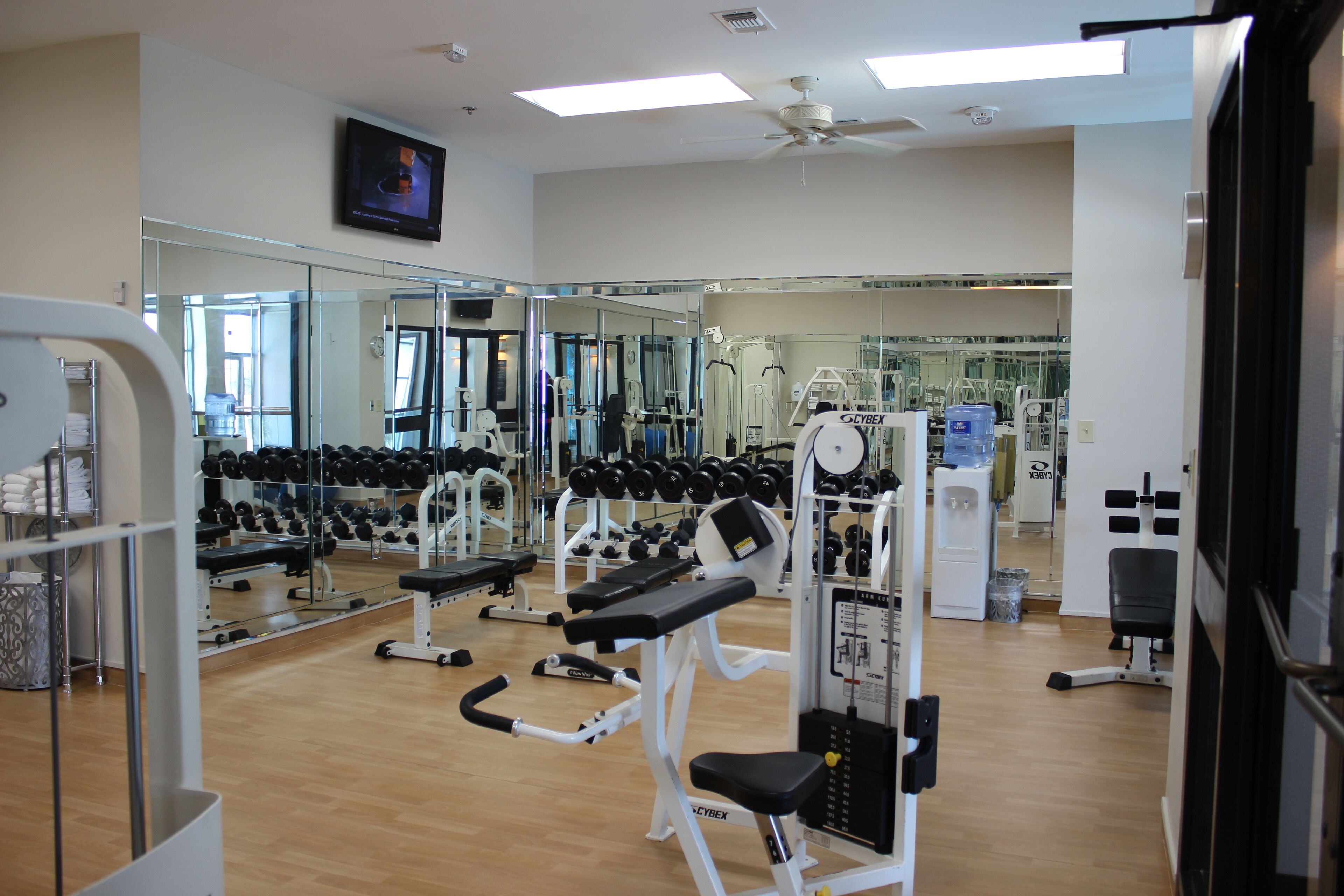A gym with exercise equipment, mirrors, and a television.