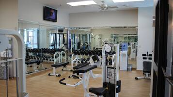 A gym with exercise equipment, mirrors, and a television.