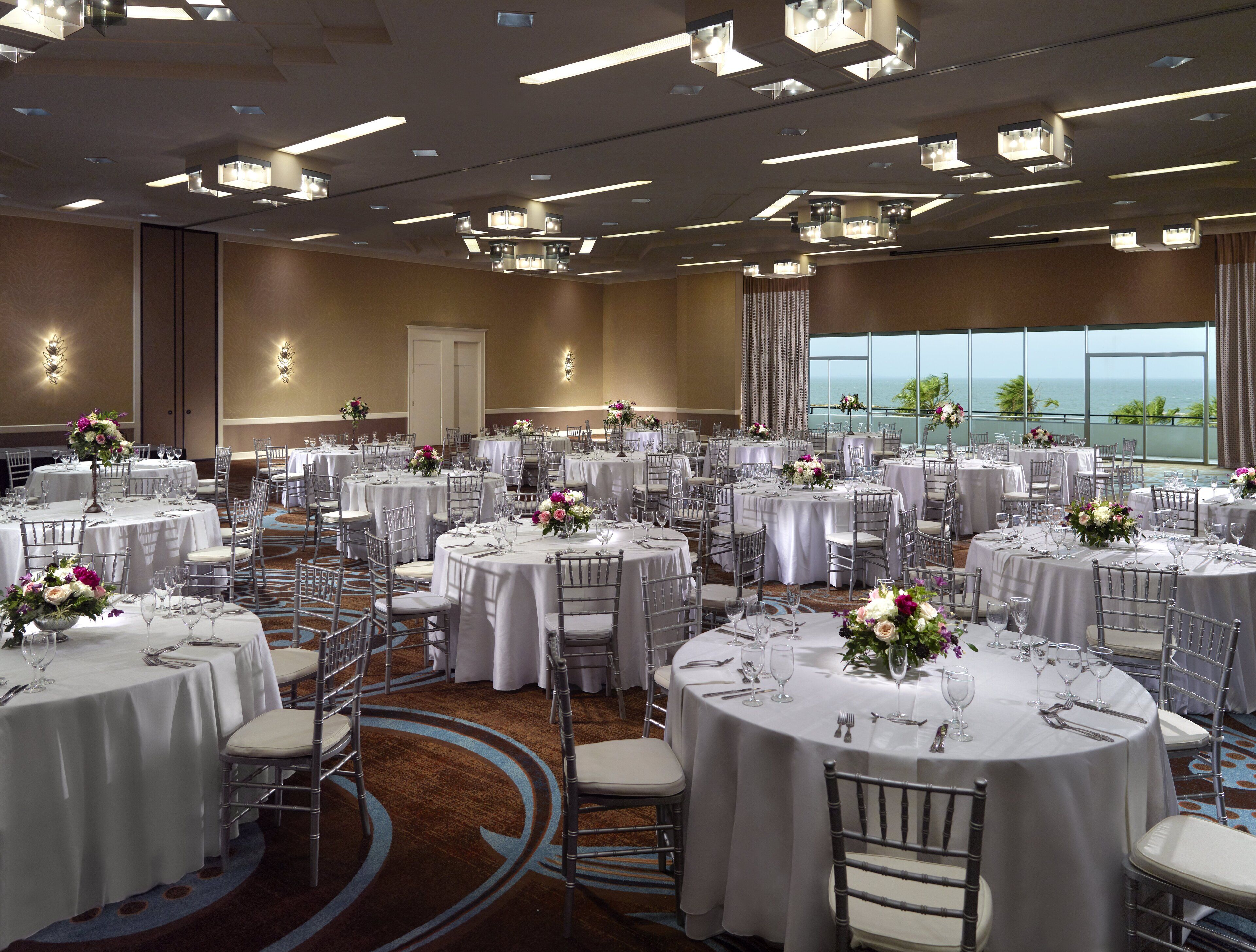 A large banquet hall with round tables set for dining, equipped with chairs and table settings.