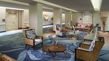 A spacious lobby with a blue patterned carpet, wicker furniture, and a sign for the "Partnership Board Room".