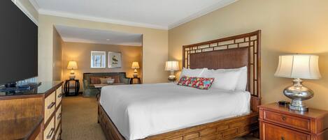 A hotel room with a large bed, wooden headboard, bedside lamps, a flat-screen TV, and a wooden dresser.