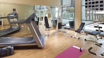 Une salle de sport équipée de machines de cardio, d’appareils de musculation et d’un banc.