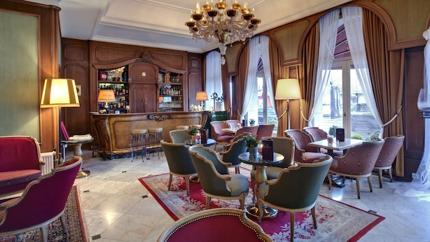 Een luxe hotellobby met een bar, een zithoek en een kroonluchter.