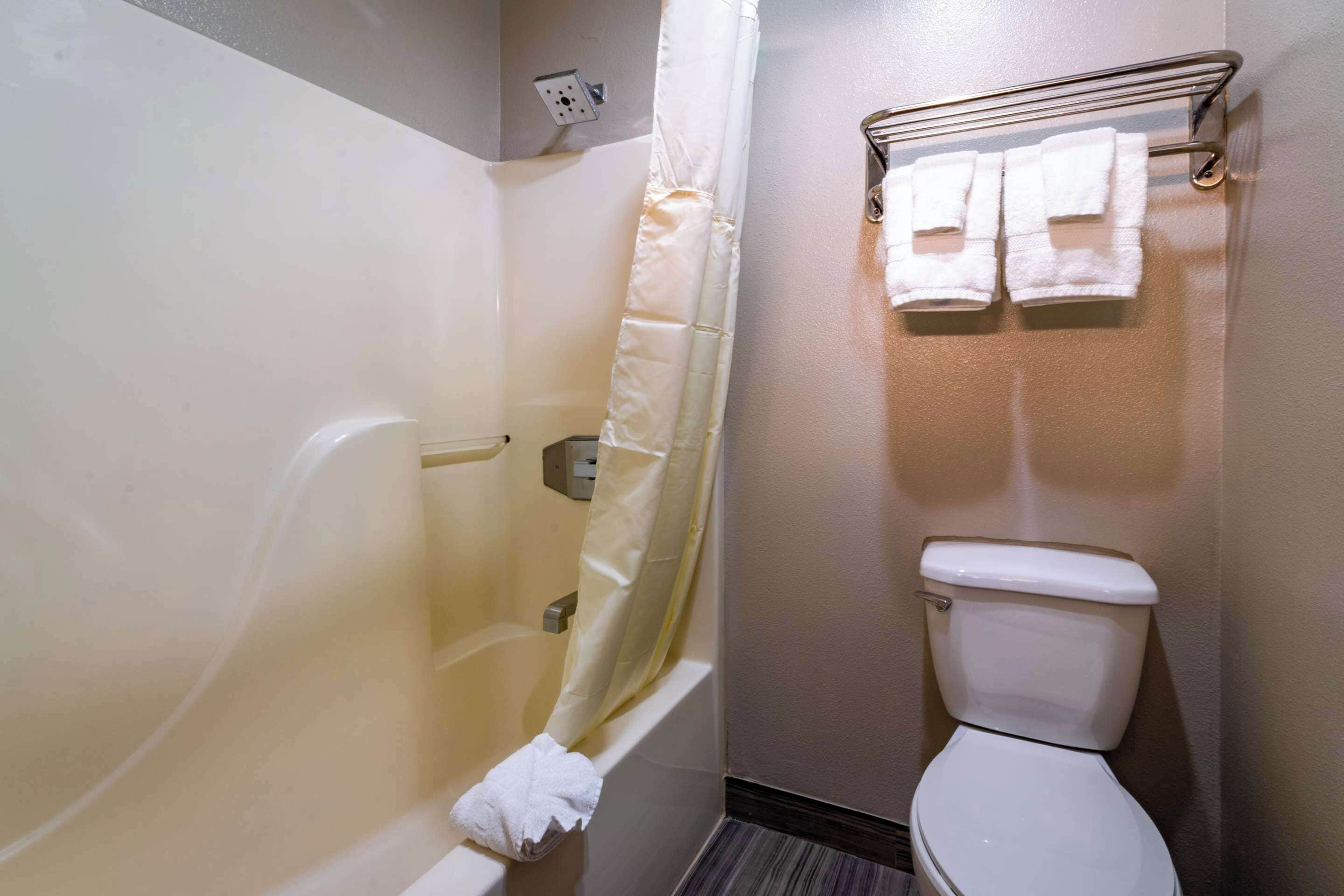 Un baño pequeño con bañera, inodoro y perchero para toallas.