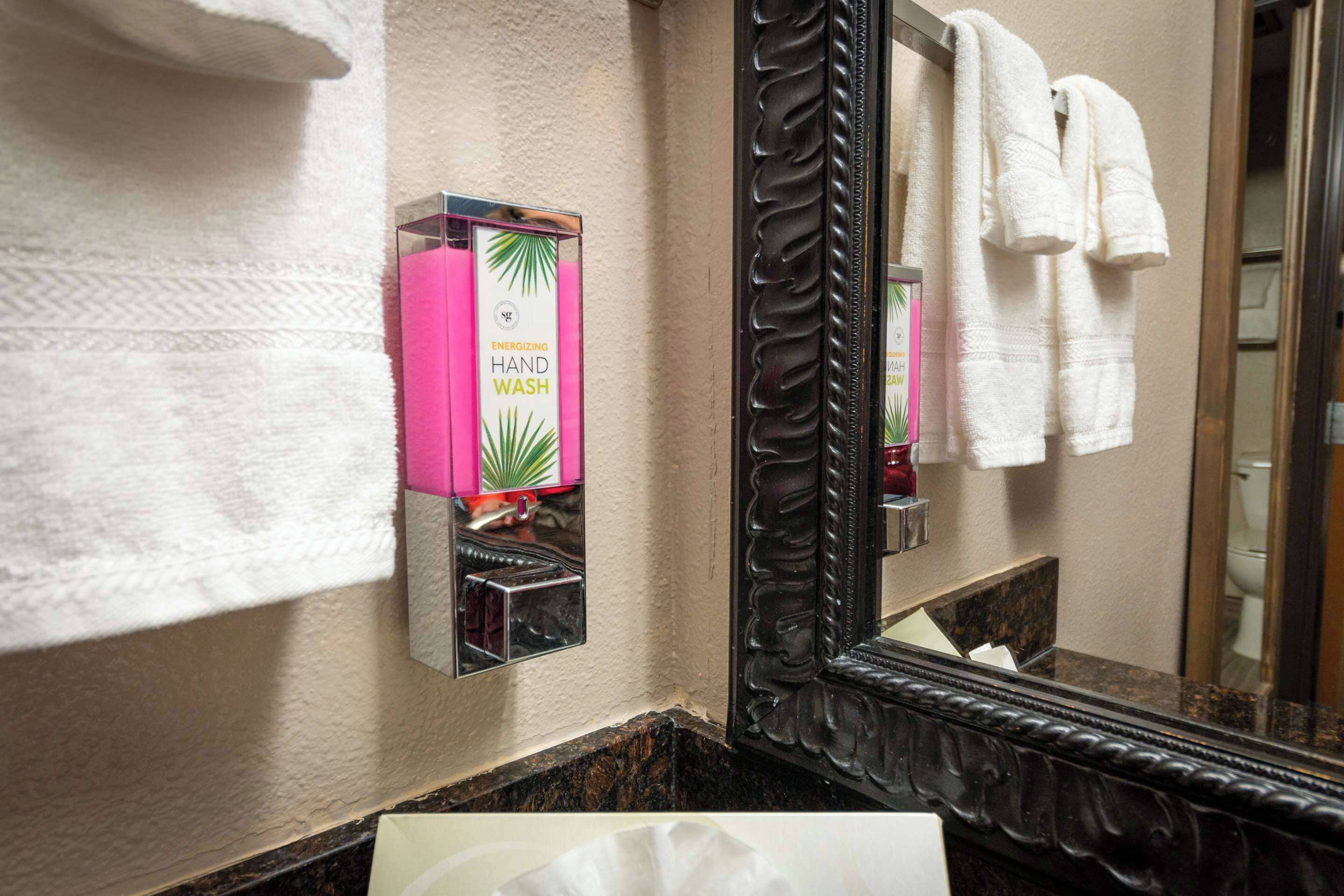 A bathroom with a hand wash station, a mirror, and towels.