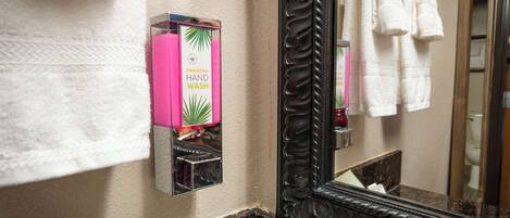A bathroom with a hand wash station, a mirror, and towels.