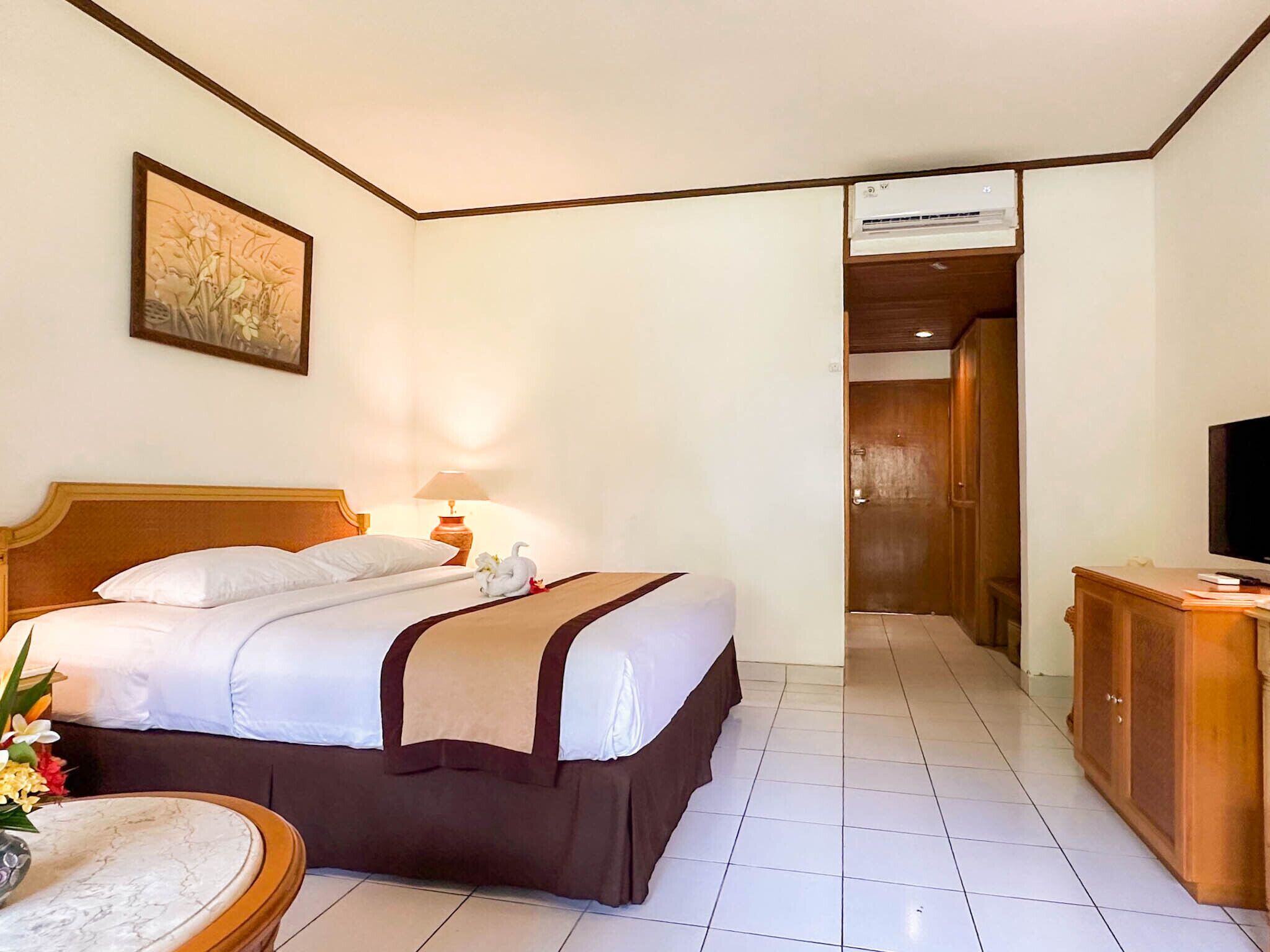 A hotel room with a bed, a bedside lamp, a TV, and a wooden wardrobe.
