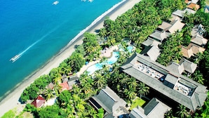 Luchtbeeld van een resort met zwembad, strand en palmbomen.