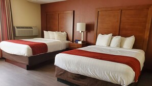 A hotel room with two beds, wooden headboards, a nightstand, a lamp, and an air conditioning unit. - Ramada by Wyndham Downtown Spokane (Spokane)