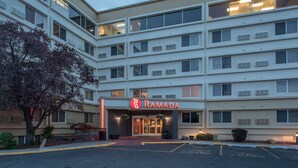 A multi-story hotel with a prominent 'Ramada' sign, featuring a modern architectural design with large windows and a parking lot in front. - Ramada by Wyndham Downtown Spokane (Spokane)