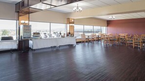 A spacious room with a long table and chairs, large windows, and a vending machine. - Ramada by Wyndham Downtown Spokane (Spokane)