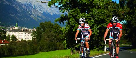 Two cyclists on a road with a mountain backdrop.