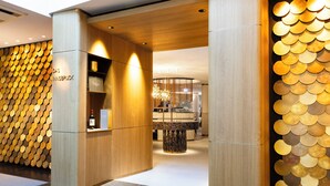 Ein modernes Interieur mit einer Holzwand, einer zentralen Sitzgruppe und einer Wand mit kreisförmigen Mustern.