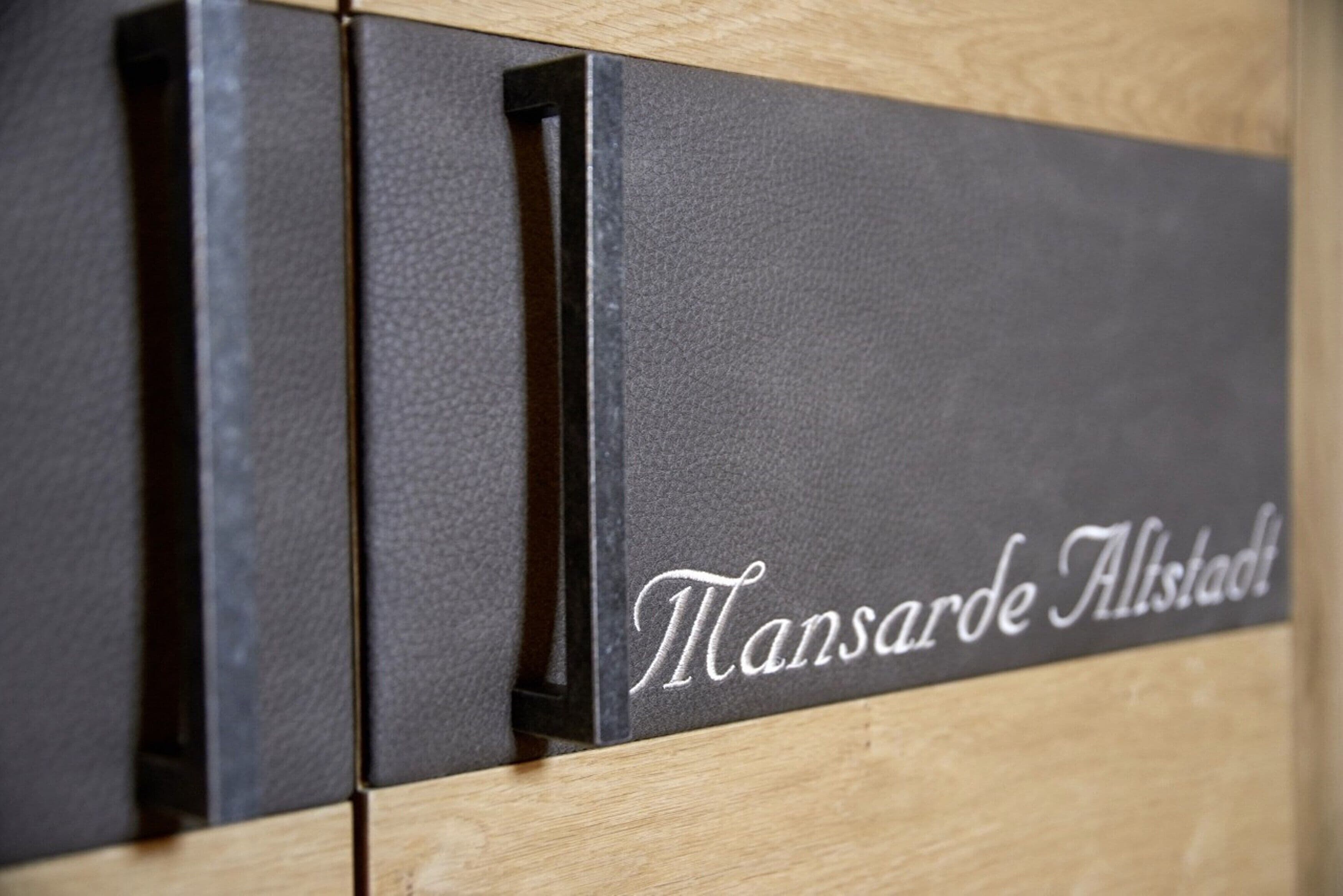Pared negra con textura y la inscripción "Mansarde Alstad".