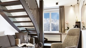 Ein modernes Wohnzimmer mit Treppe, Sofa, Sessel und Ottomanen in Rot.