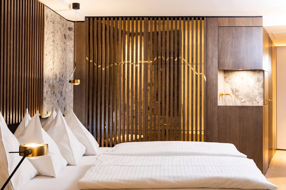 Quarto moderno com cama, painel de madeira ripa e lareira de mármore.