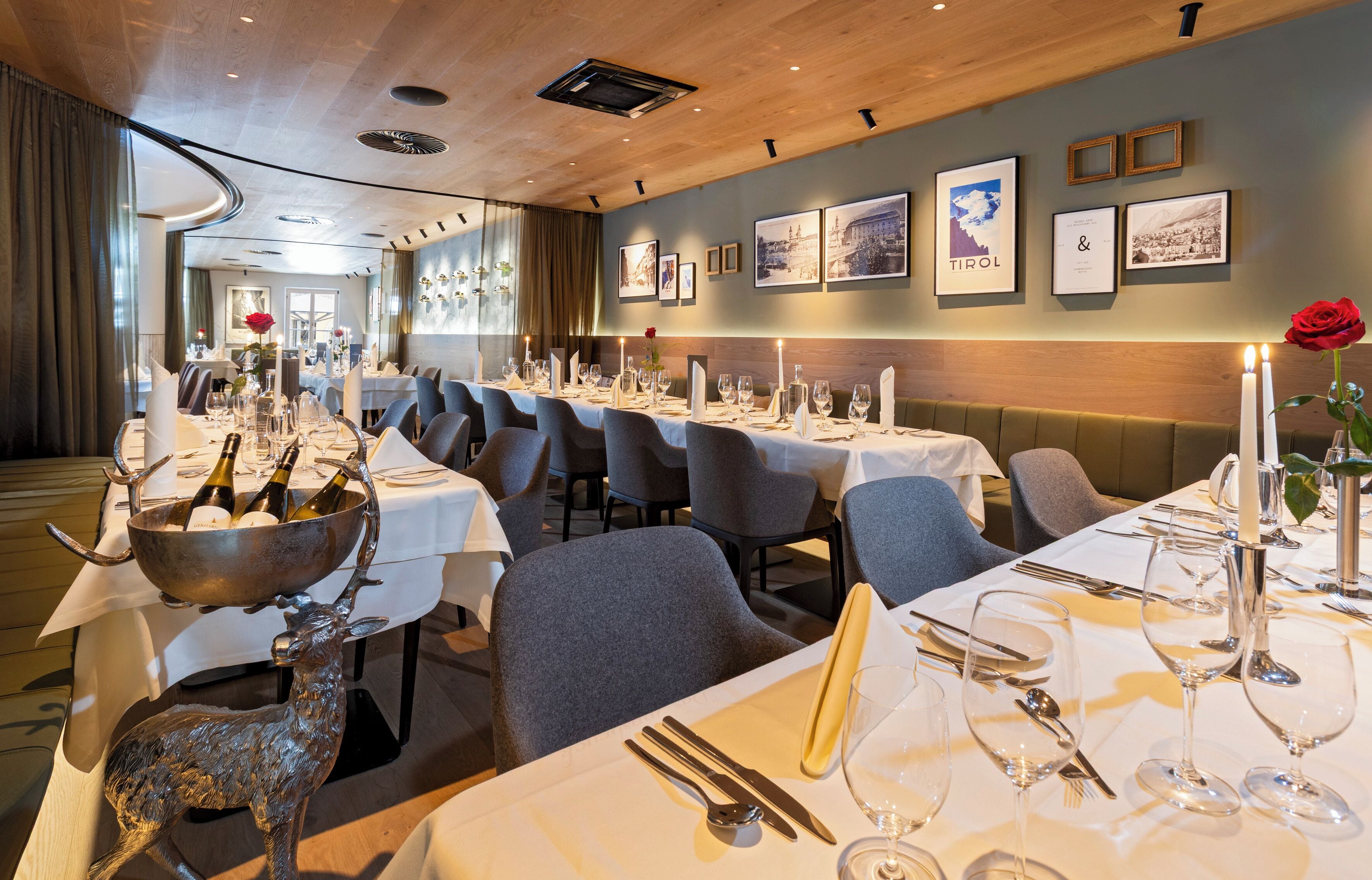Un restaurante con mesas largas dispuestas para comer, velas y una estatua decorativa de un ciervo.