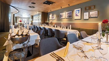 Un restaurante con mesas largas dispuestas para comer, velas y una estatua decorativa de un ciervo.