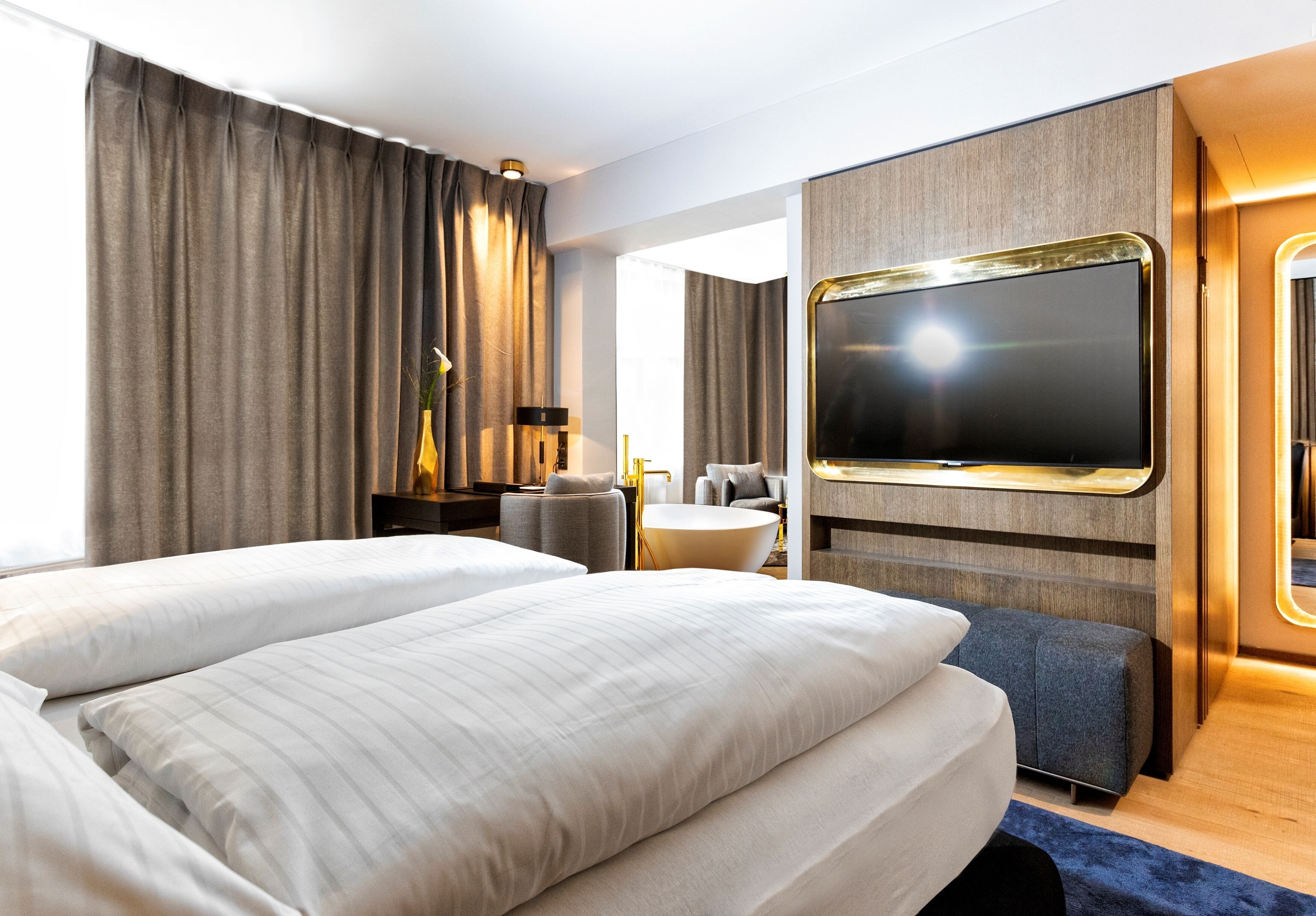 A hotel room with two beds, a flat-screen TV, a desk, and a seating area.