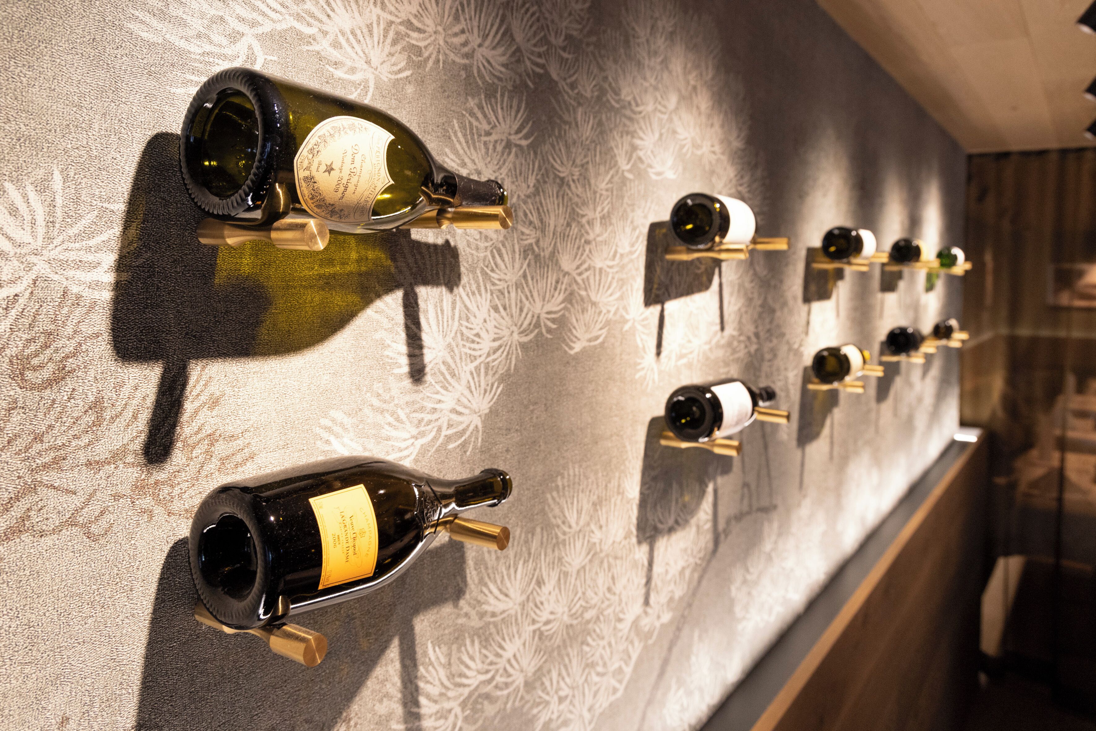 A wall with multiple wine bottles displayed on shelves.
