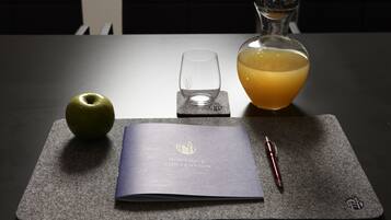 A table with a notebook, a pen, a glass, and a bottle of orange juice.