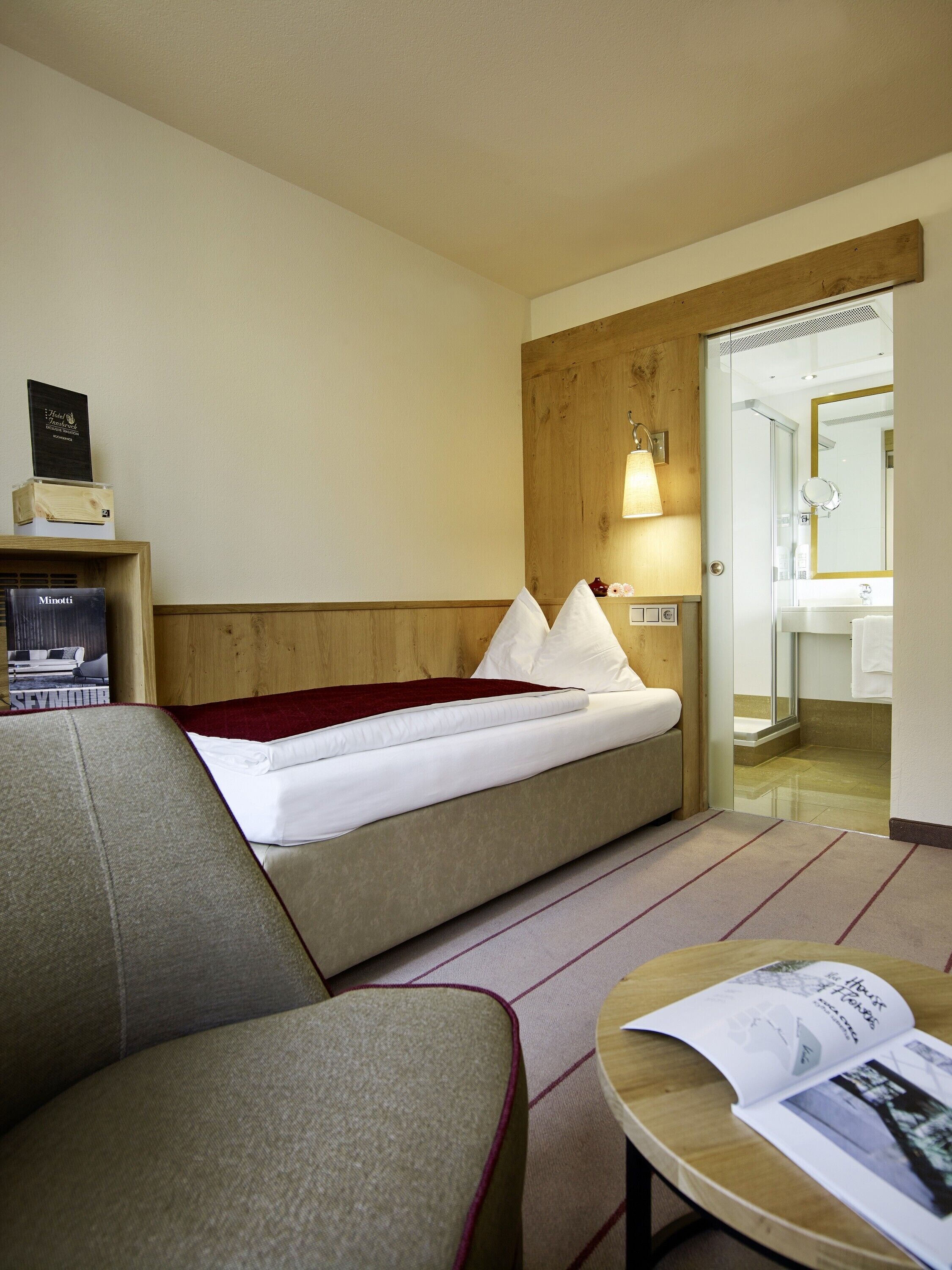 Ein Hotelzimmer mit Bett, Sofa, einem kleinen Tisch und einem durchgegangenen Tür erkennbaren Badezimmer.