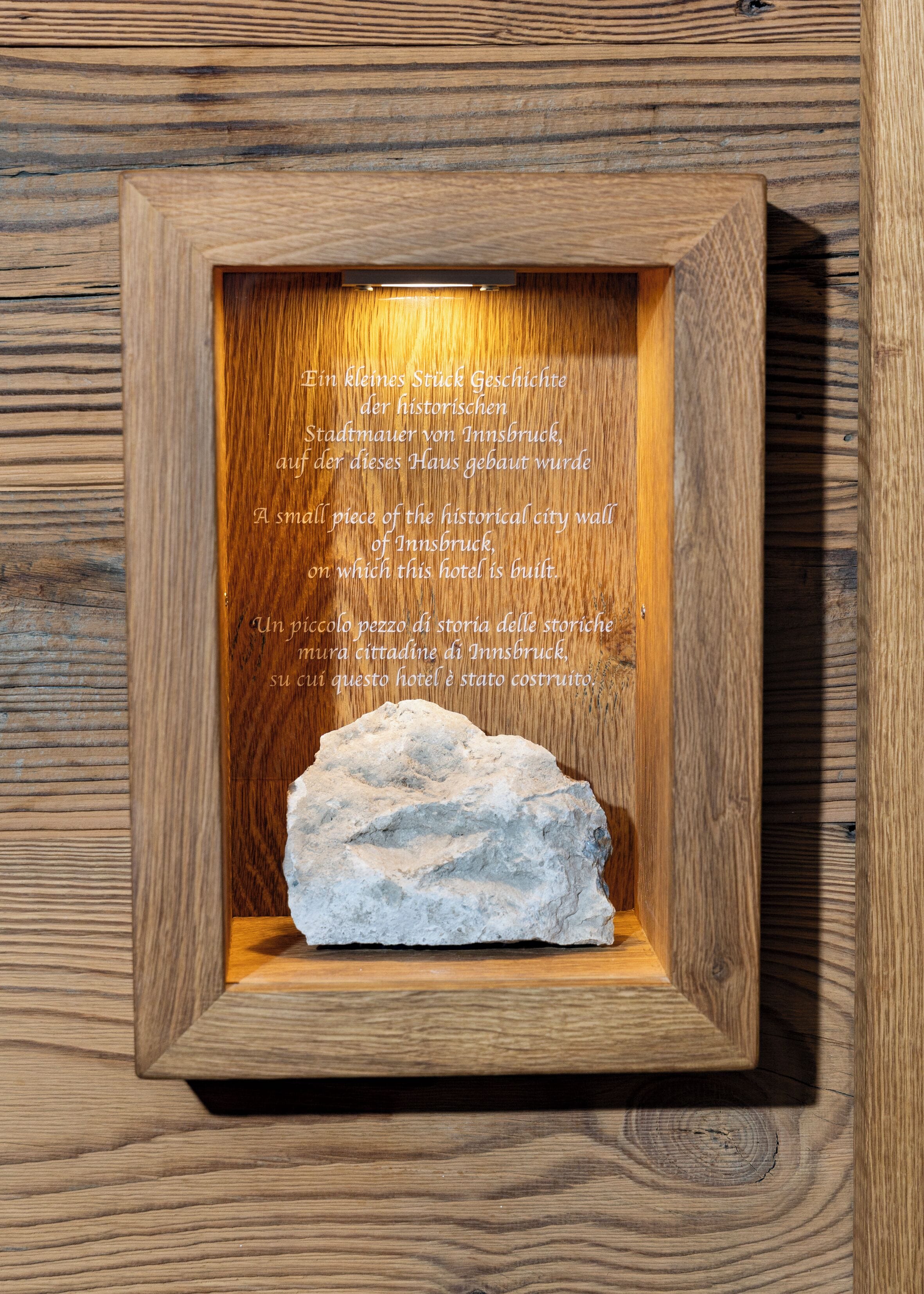 A framed display with a piece of stone and text describing its historical significance related to Innsbruck's city wall.