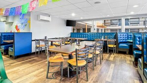 Un restaurante con cabinas y mesas, un letrero de neón y un televisor en la pared.