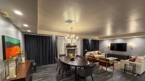 A modern living room with a dining area, a fireplace, and a flat-screen TV. - Crowne Plaza Phoenix - Chandler Golf Resort by IHG (Chandler)