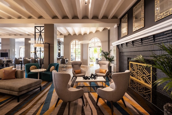 A spacious lounge area with modern furniture, a fireplace, and large windows. - Crowne Plaza Phoenix - Chandler Golf Resort by IHG (Chandler)
