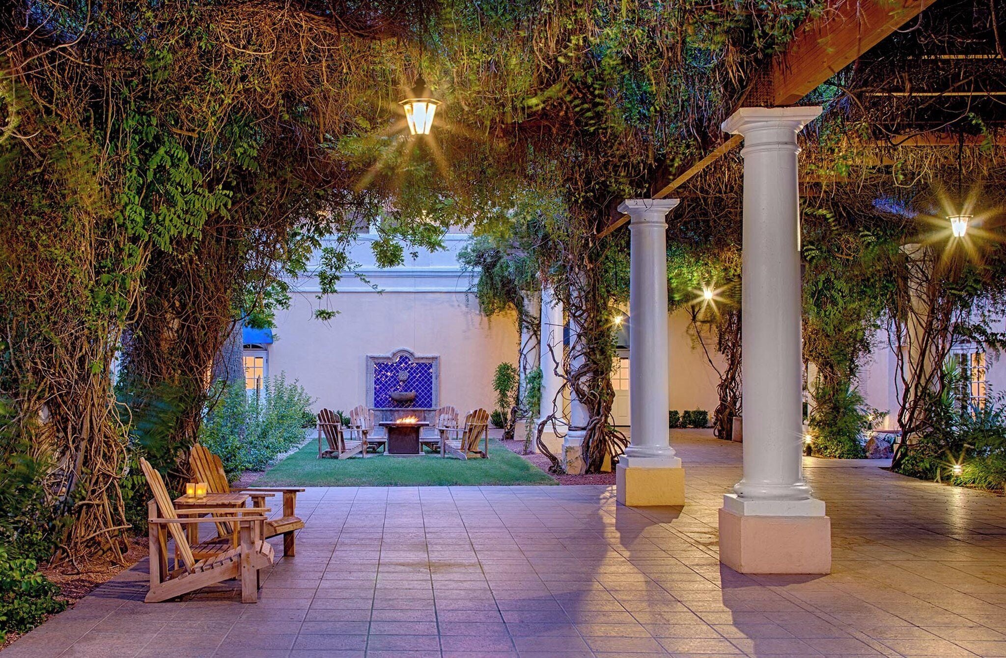 Un espacio de patio al aire libre con una chimenea, asientos y columnas.