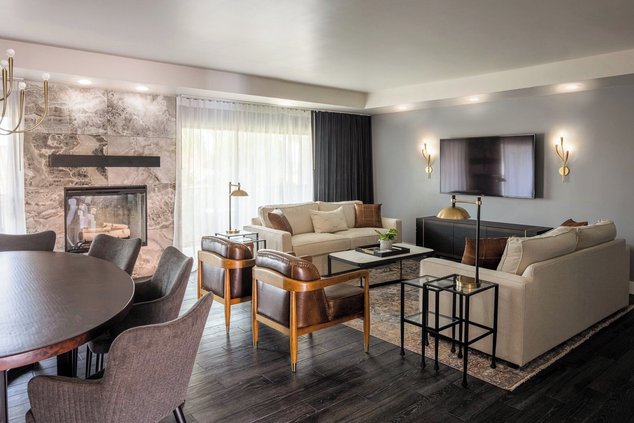 A modern living room with a fireplace, a flat-screen TV, and a dining area with a round table and chairs.
