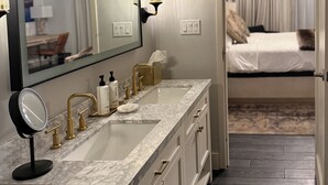 A hotel bathroom with a large mirror, a sink with gold fixtures, and a vanity with drawers. - Crowne Plaza Phoenix - Chandler Golf Resort by IHG (Chandler)